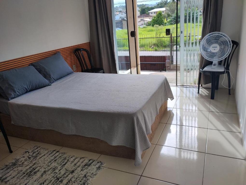 a bedroom with a bed and a balcony with a fan at Casa das Embaúbas 1 in São José