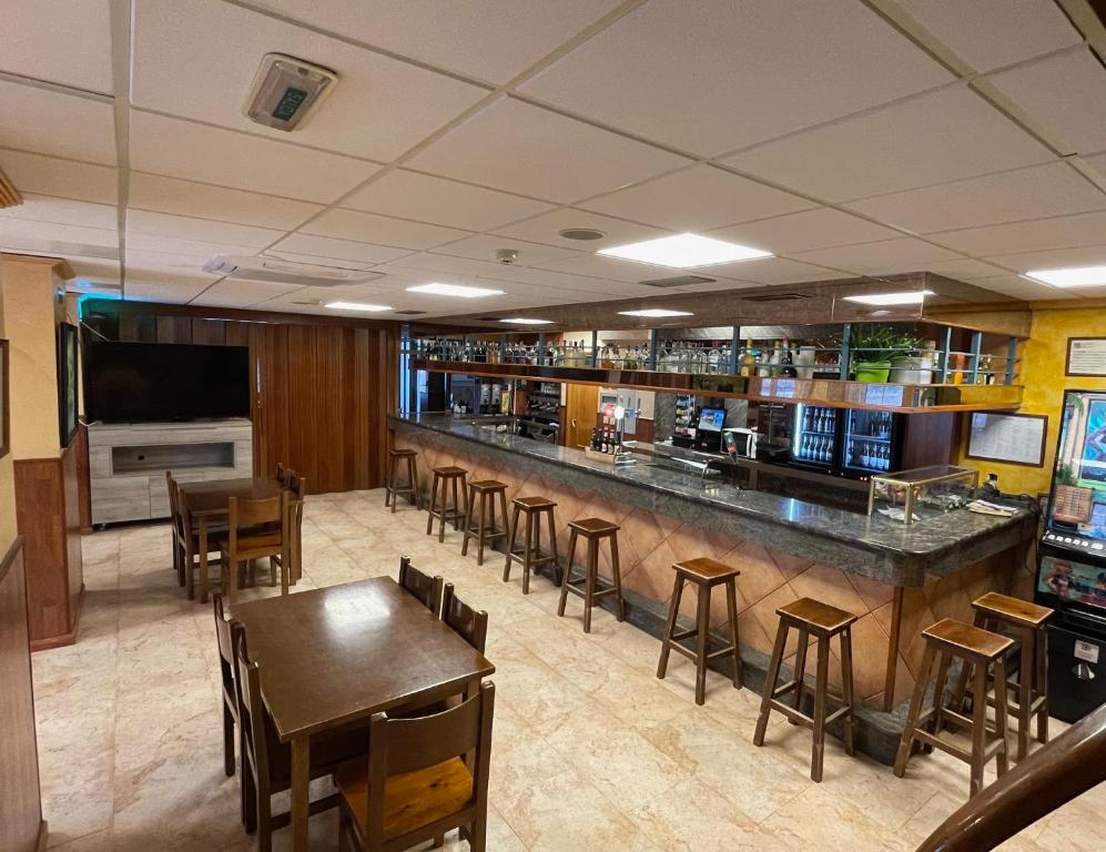 eine Bar in einem Restaurant mit Holztischen und -stühlen in der Unterkunft Hostal El Corzo in Villafranca