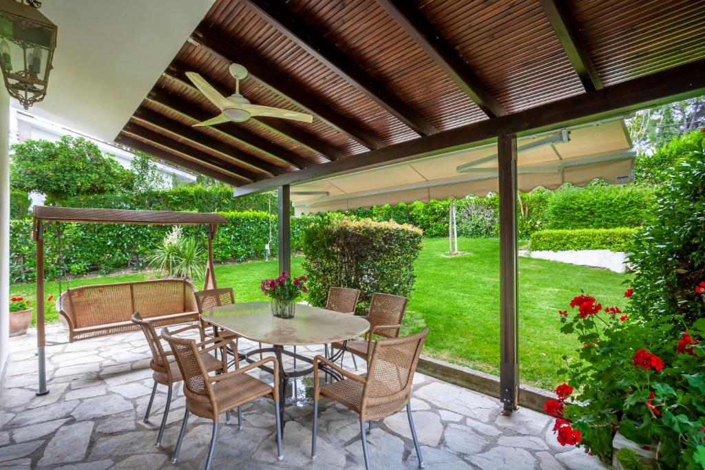 a patio with a table and chairs under a pergola at Luxurious Sani Villa Luna with shared pool in Sani Beach