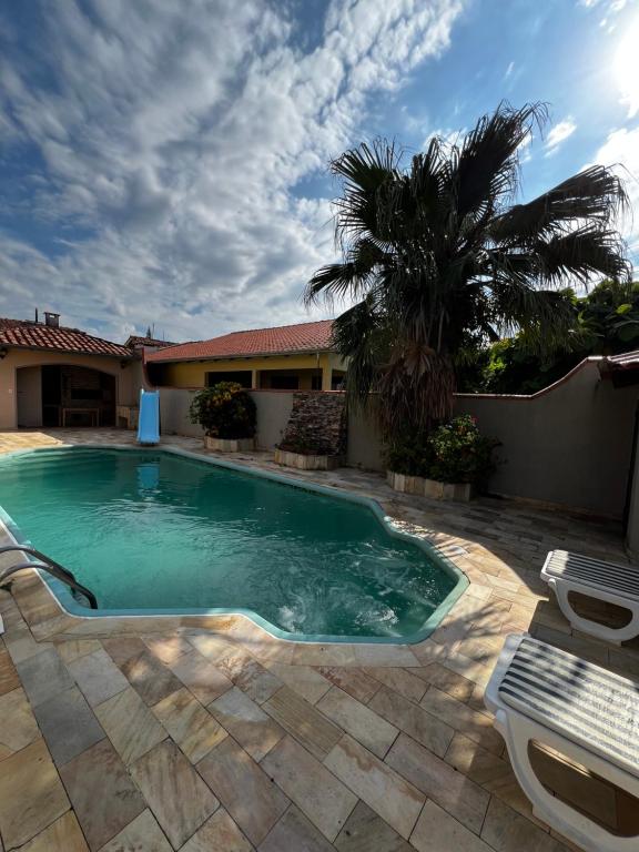 a swimming pool in a yard with a palm tree at Pousada Casa Chico in Navegantes