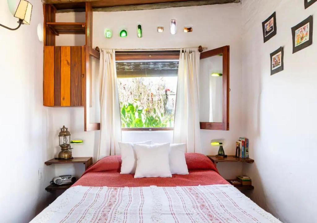 a bedroom with a bed with a red blanket and a window at La Casa del Hornero in Piriápolis
