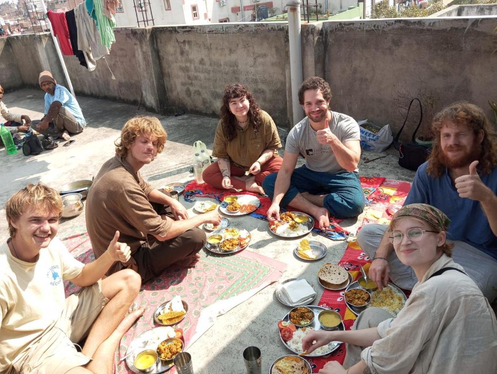 um grupo de pessoas sentadas no chão comendo comida em Darbar Homestay em Gaya