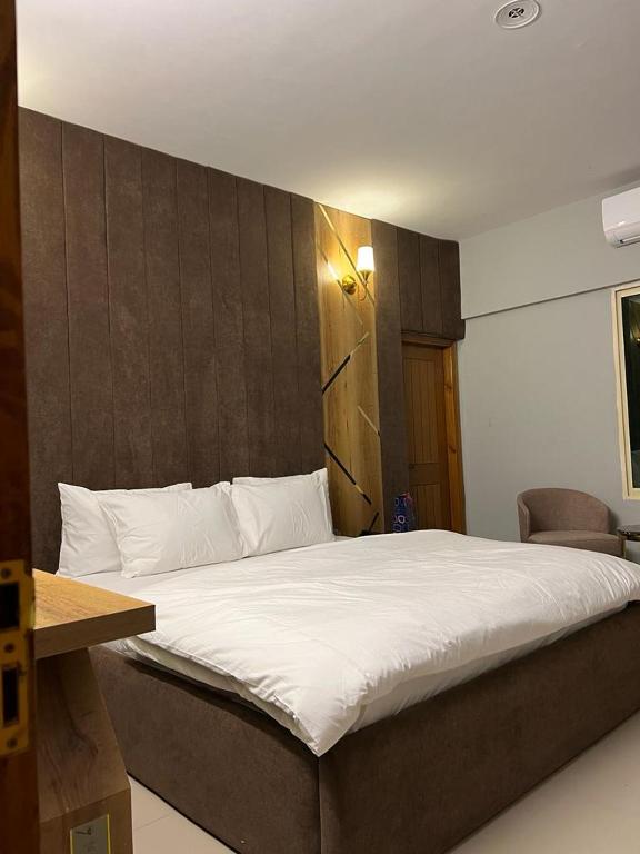 a bedroom with a large bed with white sheets at Marigold Accommodations in Karachi