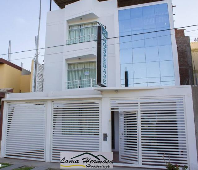 ein weißes Gebäude mit vielen Türen davor in der Unterkunft Hotel Loma Hermosa in Piura