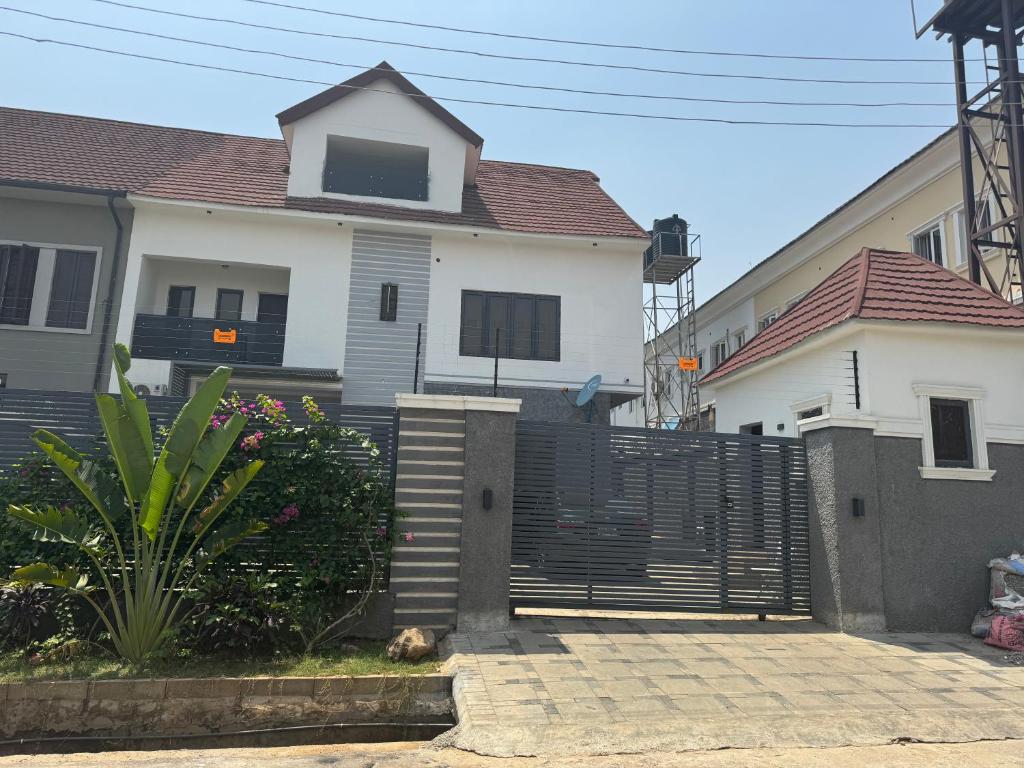 une maison blanche avec une clôture devant elle dans l'établissement Jazeera Apartments, à Abuja