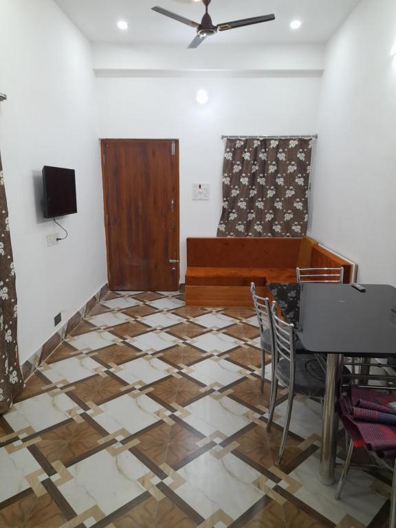 een kamer met een piano en een tafel en stoelen bij Gunjan Cottage in Deoghar