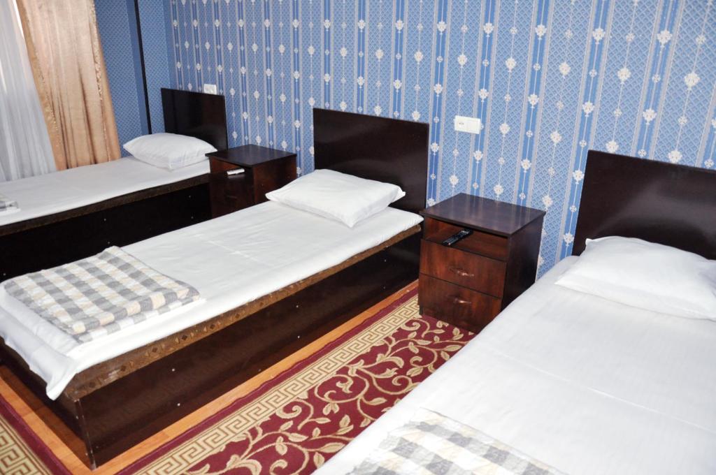 two beds in a room with blue walls at Шинам Мехмонхонаси in Eshonguzar