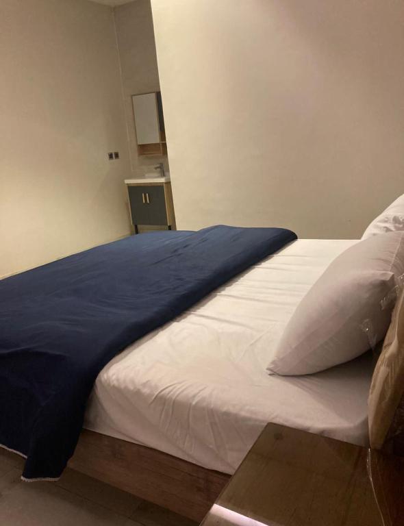 Una cama con una manta azul encima. en شاليه خاص vip الشقيق-الدرب, en Ash Shuqayq