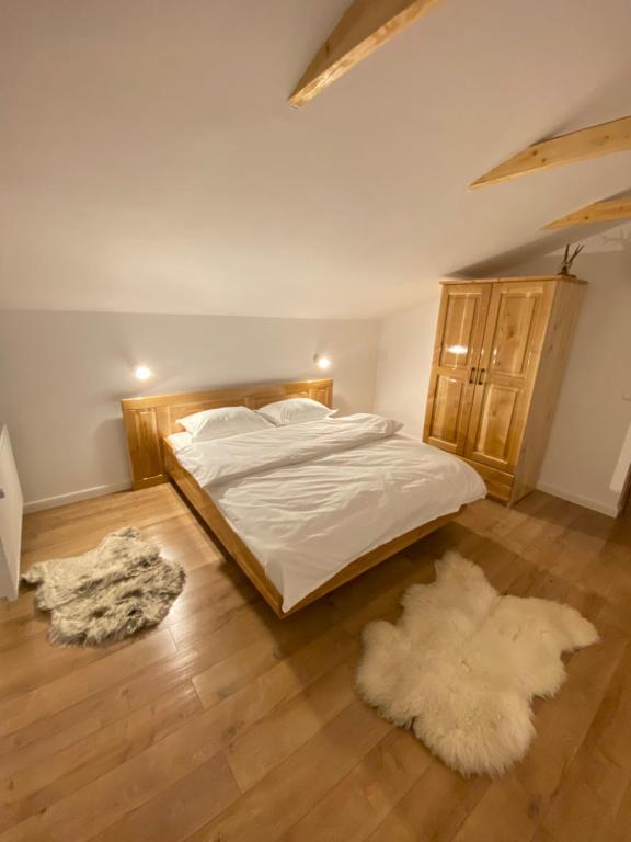 a bedroom with a bed with white sheets and two rugs at Hirsch Chalet Apuseni in Mărgău