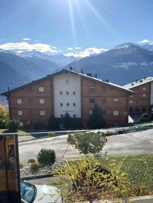 a large building with mountains in the background at Appartement Nour in Randogne