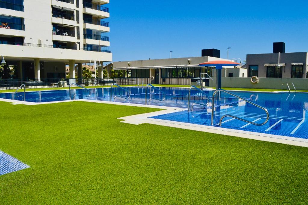 ein großer Pool mit grünem Gras neben einem Gebäude in der Unterkunft Sea View Apartment Sabbia by Gabbeach in Valencia