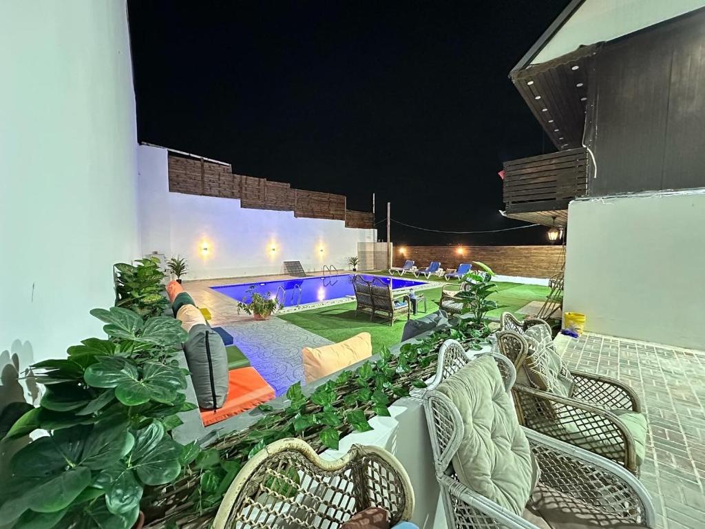 une terrasse avec des chaises et une piscine ouverte la nuit dans l'établissement Jericho Palestine, Panorama Villa- View, Full Privacy & Pool, à Jéricho