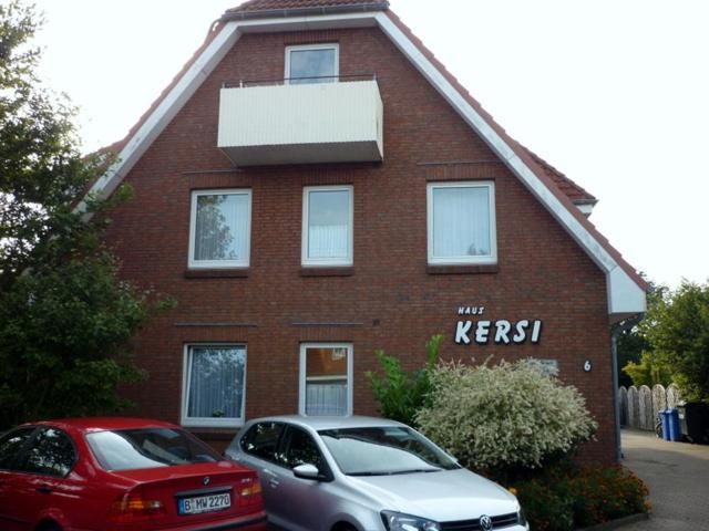 two cars parked in front of a brick house with graffiti at Haus Kersi in Büsum