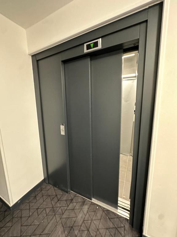 une porte d'ascenseur dans un immeuble avec un panneau. dans l'établissement Appartement pierrefitte, à Pierrefitte-sur-Seine