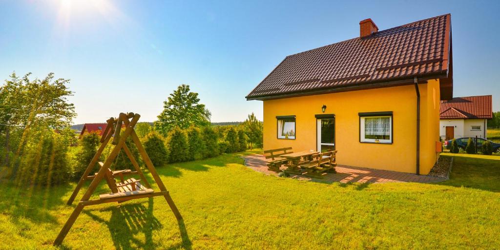 een geel huis met een houten ezel ervoor bij Domki Letniskowe Cessatio Rusinowo in Rusinowo