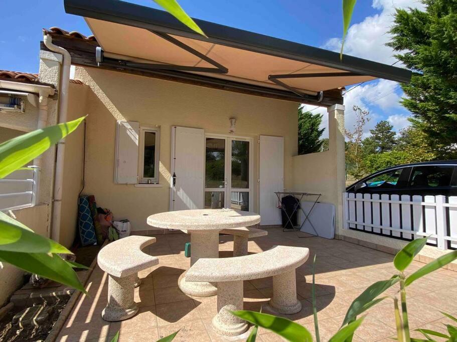 a patio with two tables and two chairs and a car at Maison de vacances avec piscine , dans résidence in Meschers-sur-Gironde