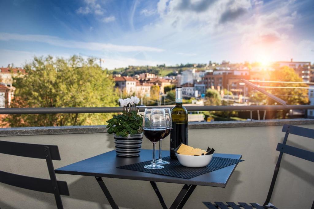 uma mesa com uma garrafa de vinho e um copo em NINARY APARTMENTS a due passi dal centro storico em Alba