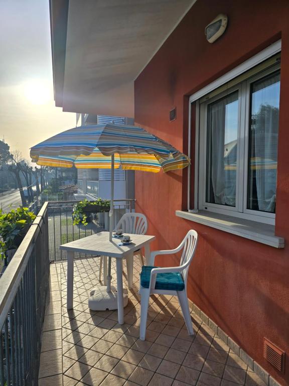 a table and two chairs and an umbrella on a balcony at Appartamento Caracola in Lignano Sabbiadoro