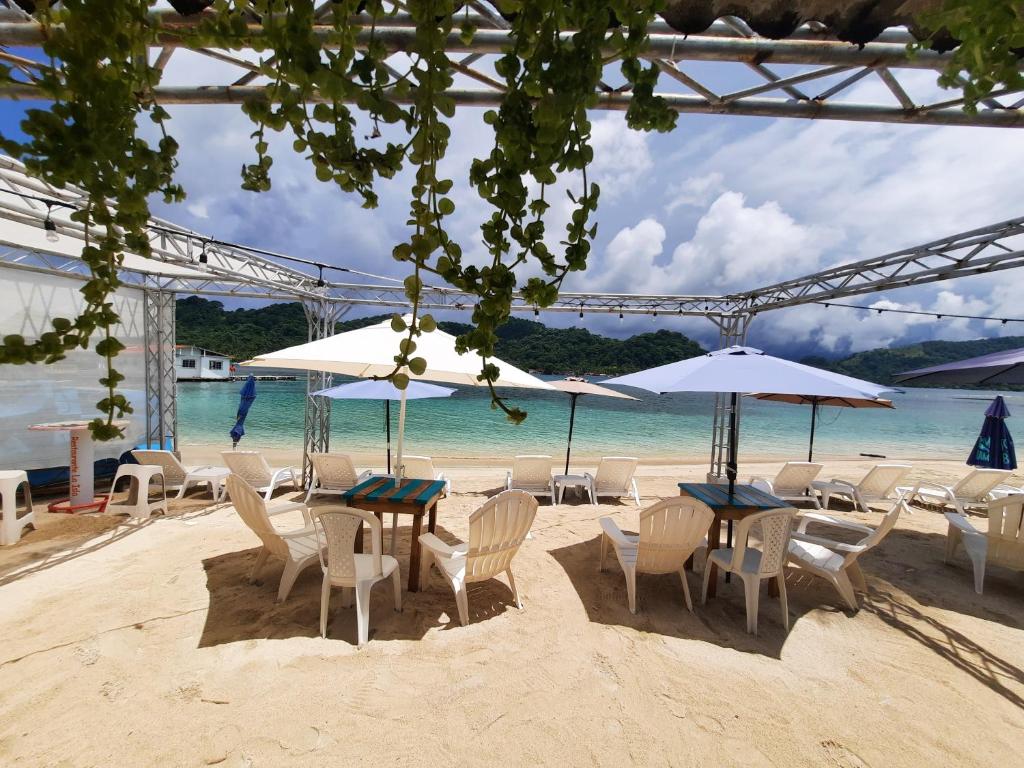 einen Strand mit Stühlen, Tischen und Sonnenschirmen in der Unterkunft Casa de playa in Isla Grande