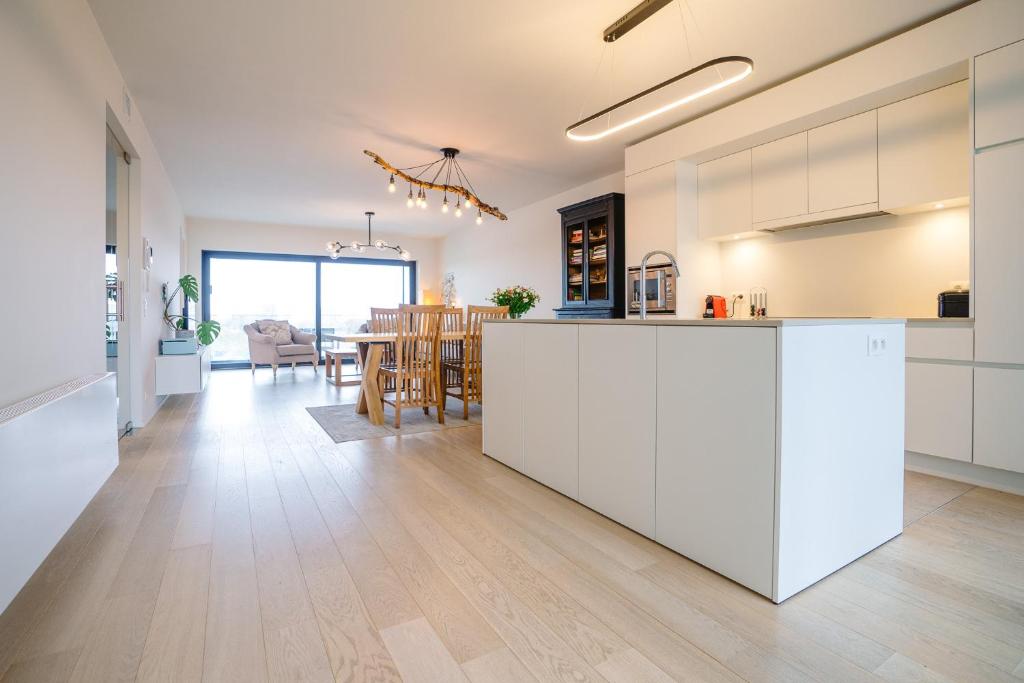 une cuisine ouverte et une salle à manger avec des armoires blanches dans l'établissement Vakantieappartement Oosteroever Oostende, à Ostende