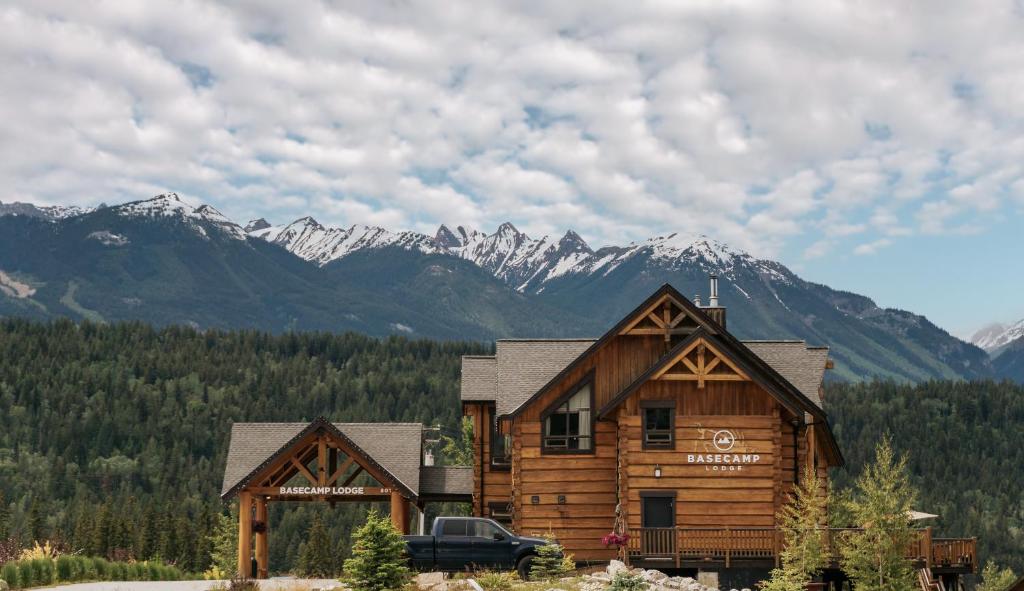 a large wooden cabin with mountains in the background at Basecamp Lodge Golden in Golden