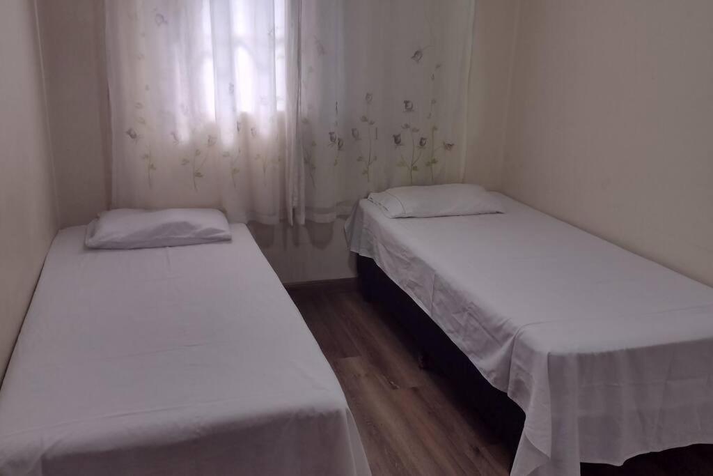 two beds in a small room with white walls at Apartamento prático, simples CDHU. in Itatiba