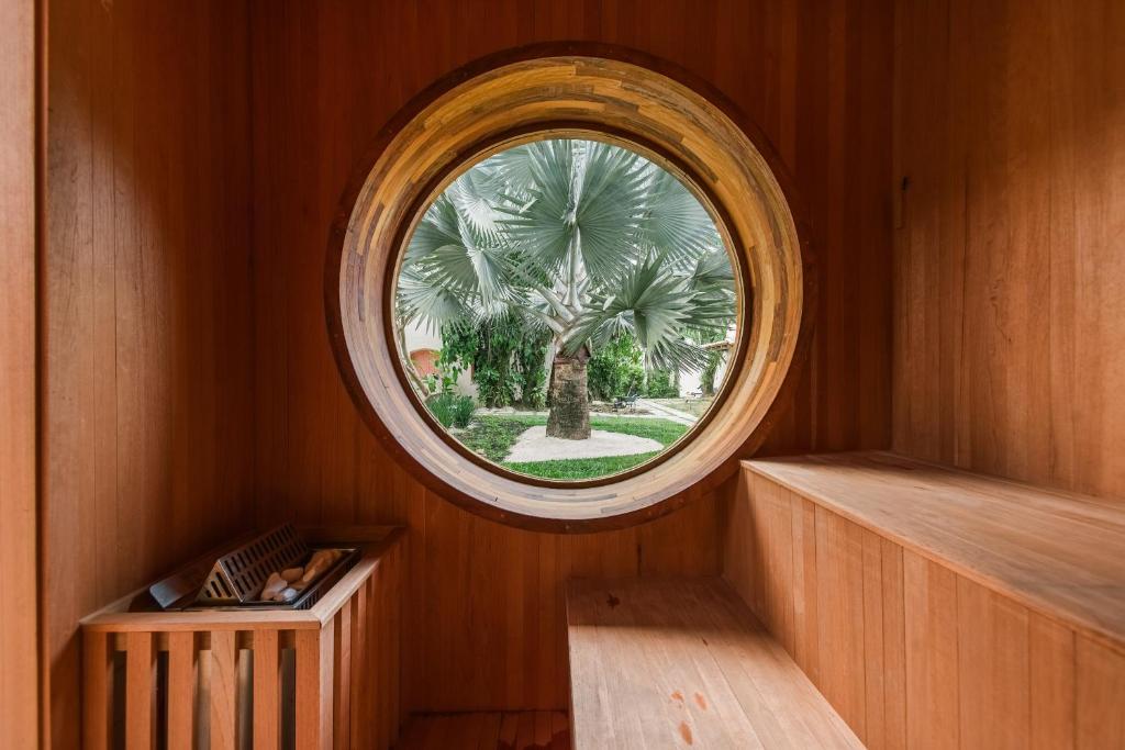 una ventana redonda en una habitación de madera con una palmera en Pousada Pazuu en Ubatuba