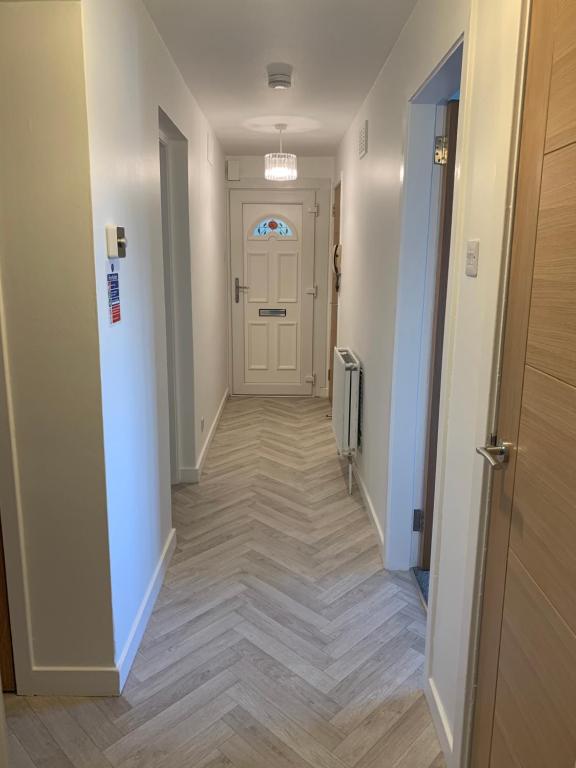 a hallway with a white door and a wooden floor at Dumfries Apartment 2 in Dumfries