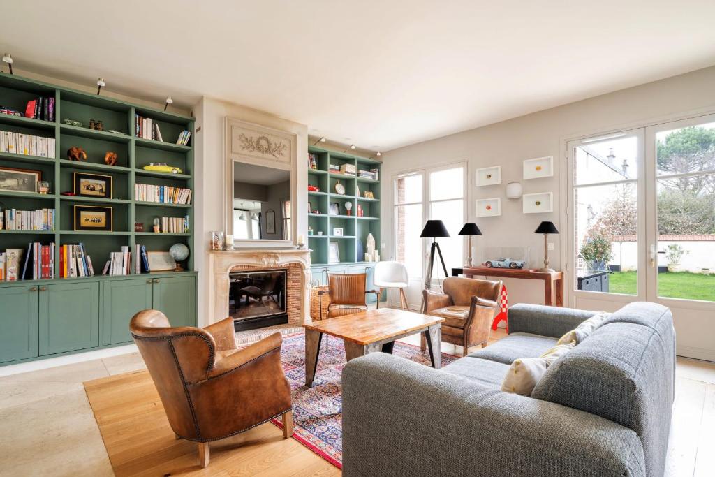 een woonkamer met een open haard en groene boekenkasten bij Large house with garden in Versailles - Welkeys in Versailles