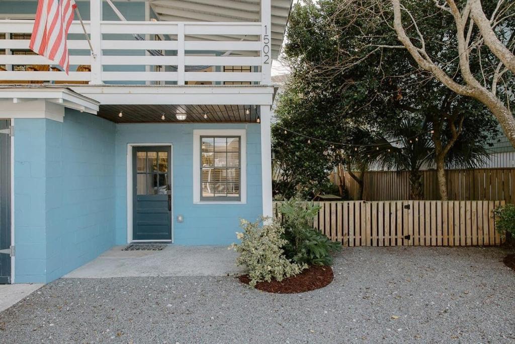 una casa azul con una puerta azul y una valla en The Bungalow Lounge by WB Abodes, en Wrightsville Beach