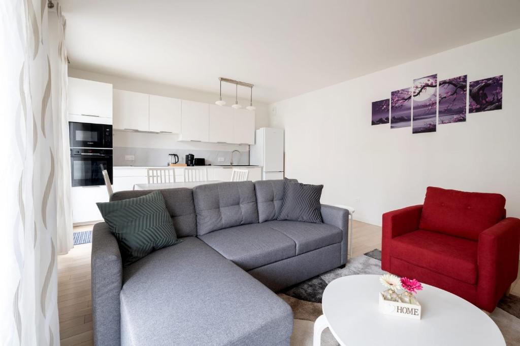 a living room with a couch and a red chair at Bright T4 with balcony in Saint-Ouen - Welkeys in Saint-Ouen