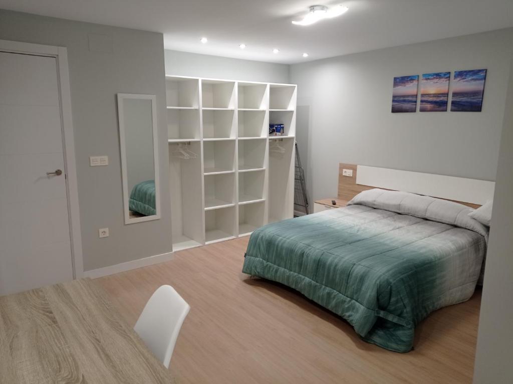 a white bedroom with a bed and a white chair at A orillas del Duero in Soria