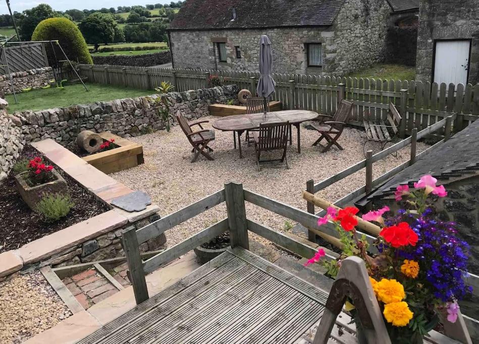 a garden with a wooden bench and a table and flowers at The Old Coop Barn in Brassington