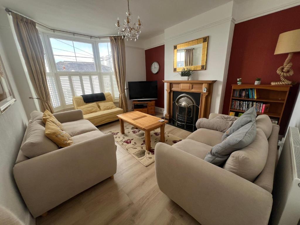 a living room with two couches and a fireplace at Spacious first floor family flat, Sea view in Torquay