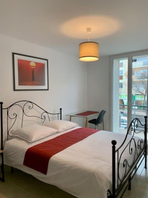 une chambre avec un lit, une table et une fenêtre dans l'établissement Grand T2 Clim & Fibre - centre universités Béziers, à Béziers