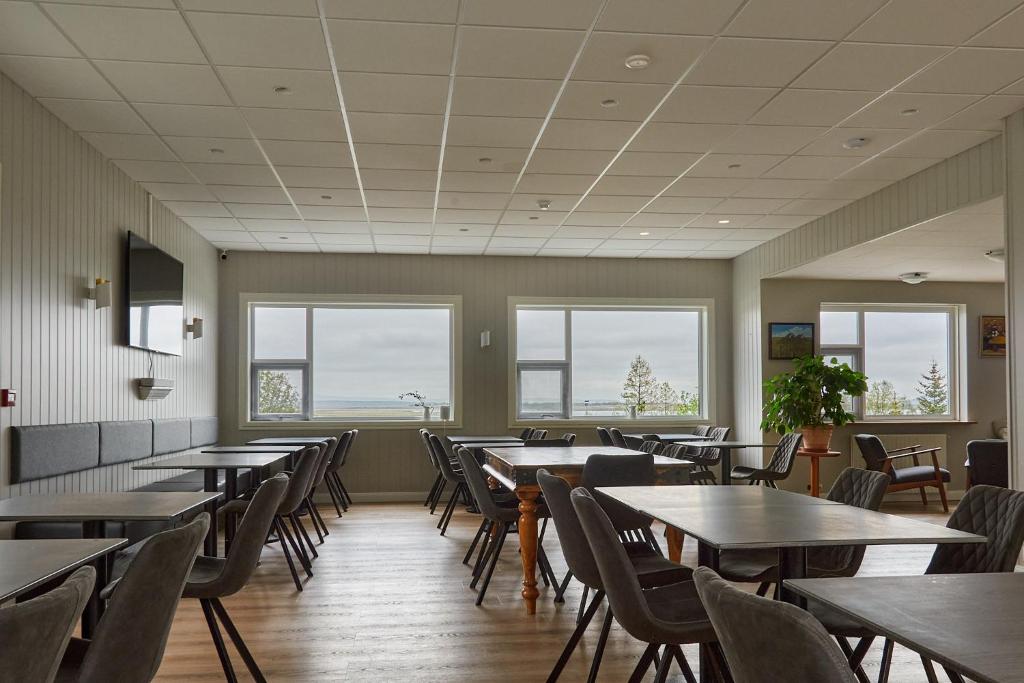Hótel Laugarvatn في لوغارفتن: غرفة طعام مع طاولات وكراسي ونوافذ