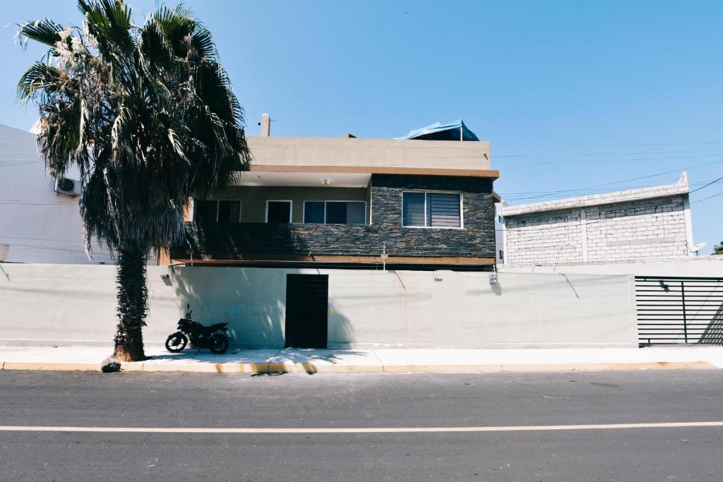 uma casa com uma moto estacionada ao lado de uma palmeira em Hostal Judy Suites em Salinas