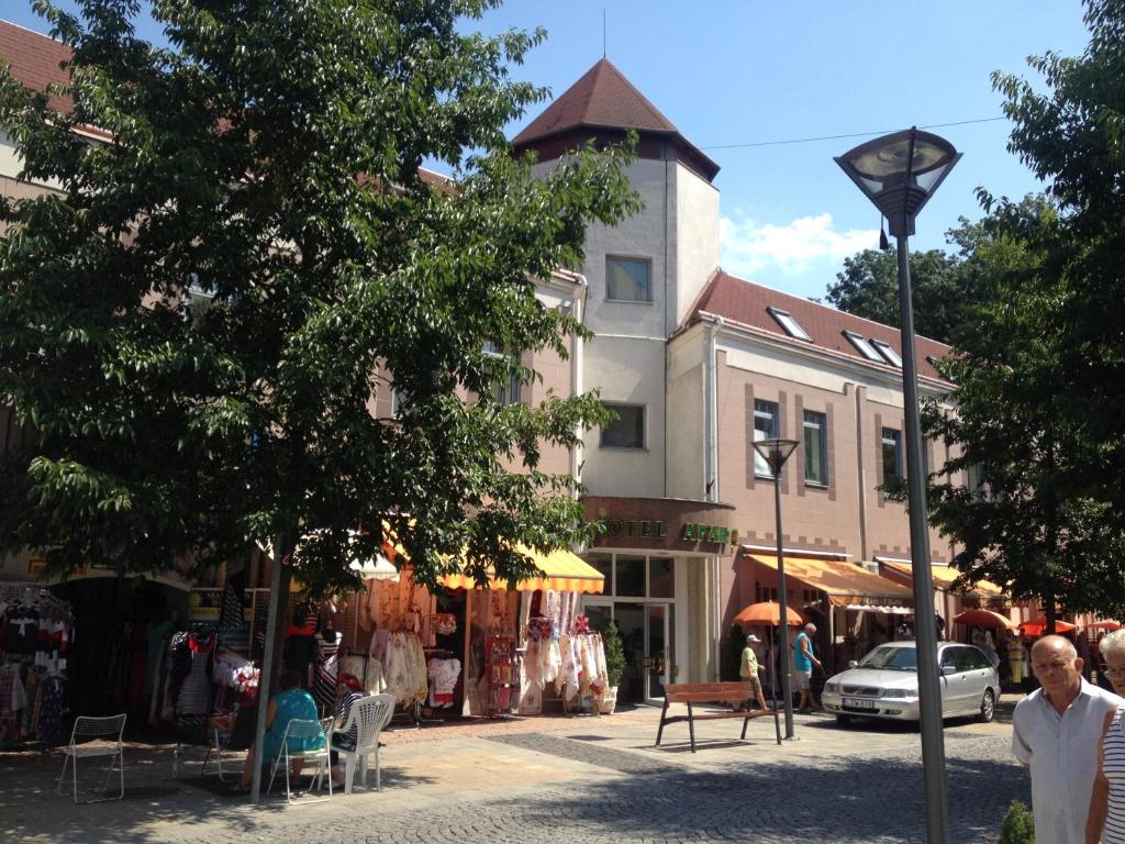 a man walking down a street in front of a building at Hotel Apart Hotel in Hévíz