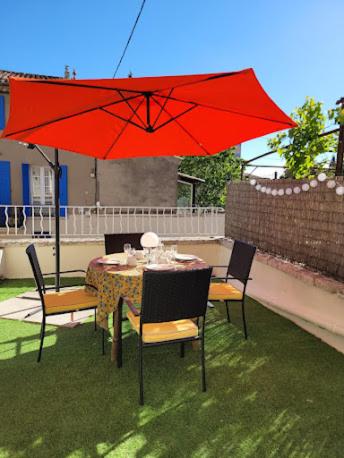 - une table et des chaises avec un parasol rouge sur la terrasse dans l'établissement Studio L'Echappée 3 étoiles, à Nyons