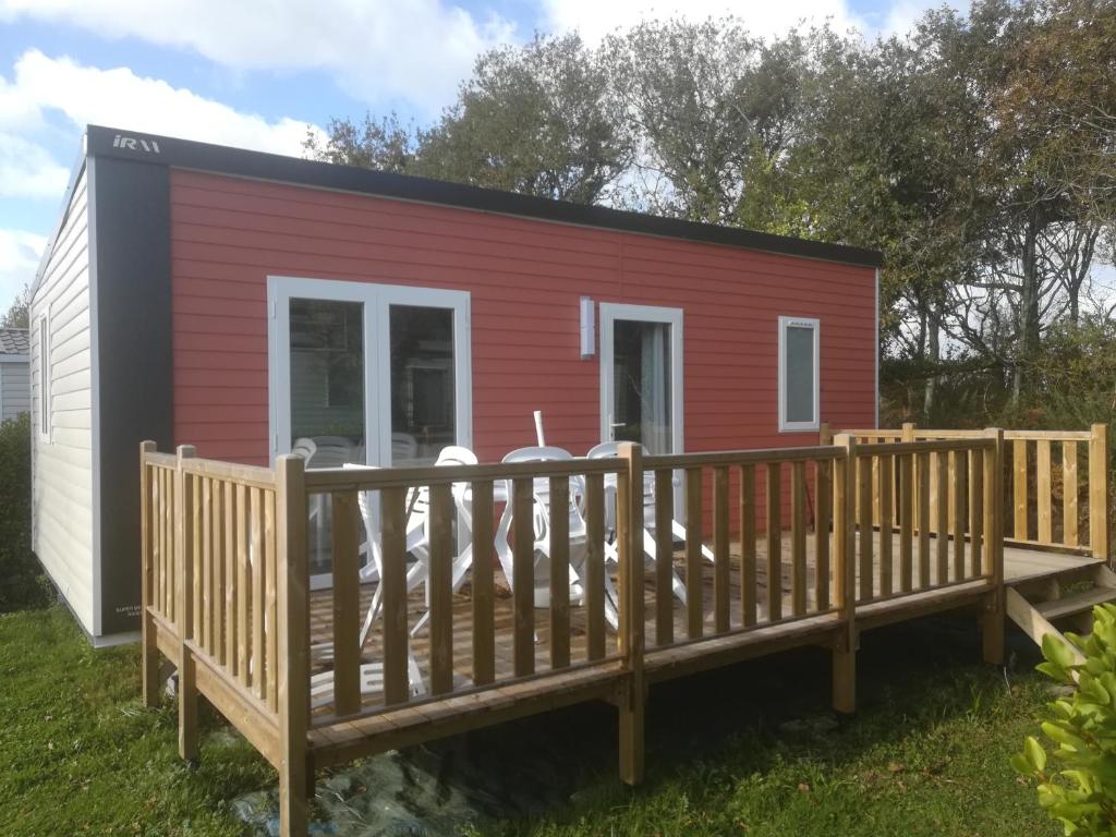 a red and black tiny house with a wooden deck at Camping de Lanven in Plomeur