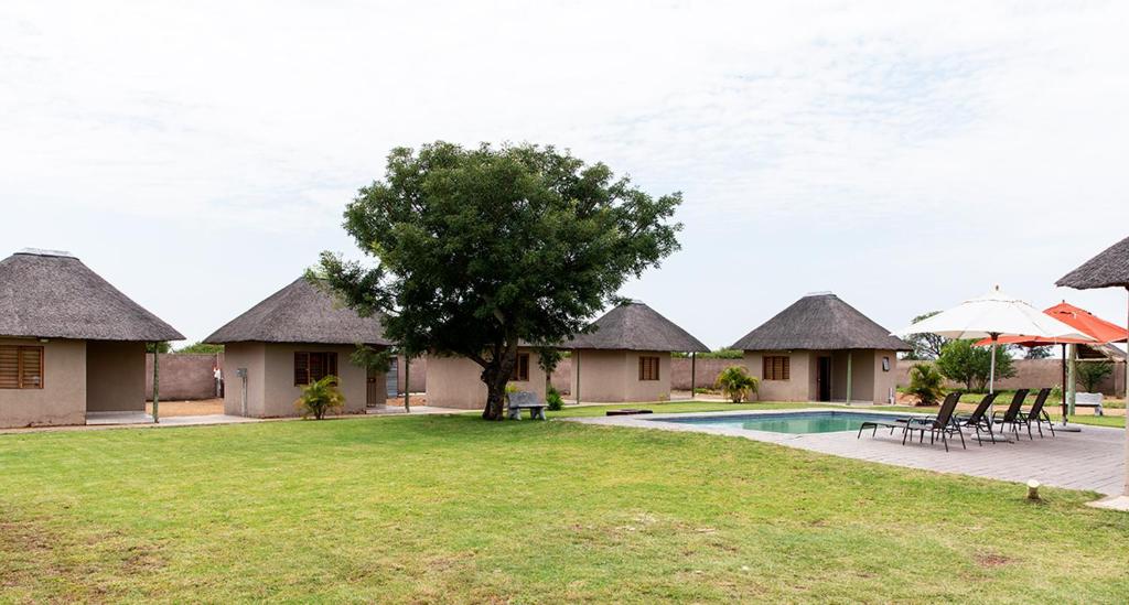 a villa with a swimming pool and a tree at In The Bush Farm Lodge in Winterveld