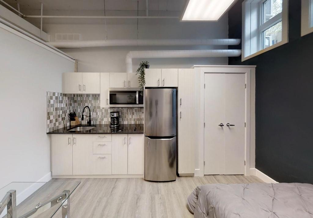 a kitchen with white cabinets and a stainless steel refrigerator at Studio in the heart of downtown in Ottawa