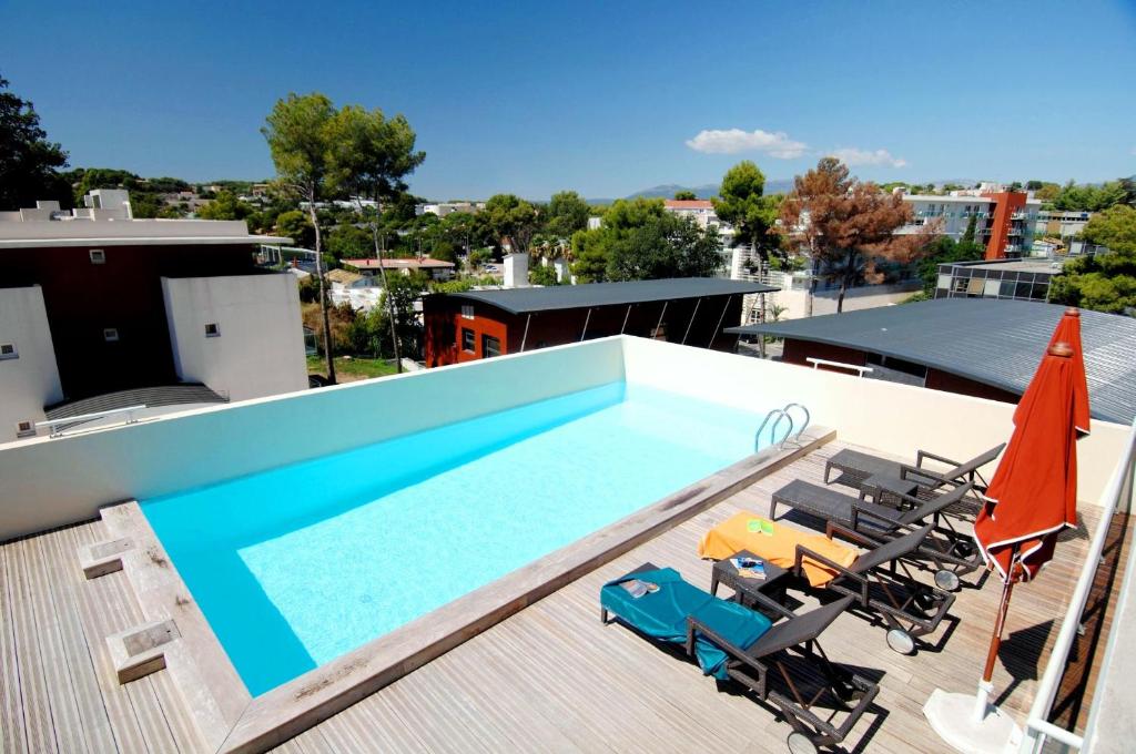 a swimming pool with chairs and umbrellas on a roof at Odalys City Antibes Olympe in Antibes