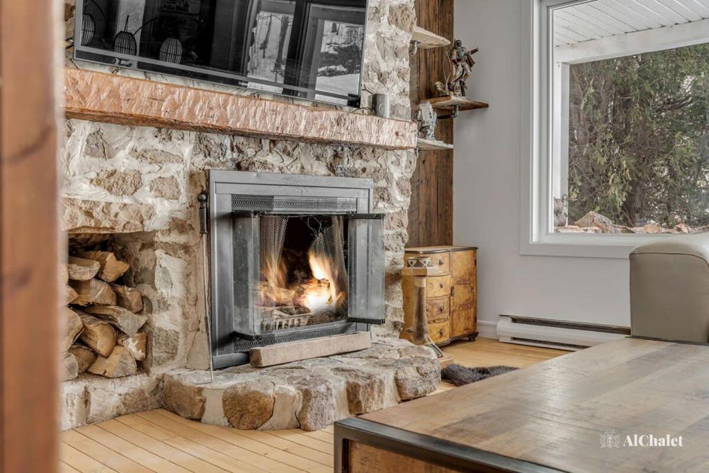 a stone fireplace in a living room with a fire at Amanaye Lodge - paisible et luxueux in Saint-Joachim