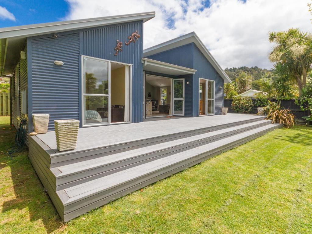 a blue house with a large wooden deck at Waihi Wonder - Waihi Holiday Home in Waihi Beach