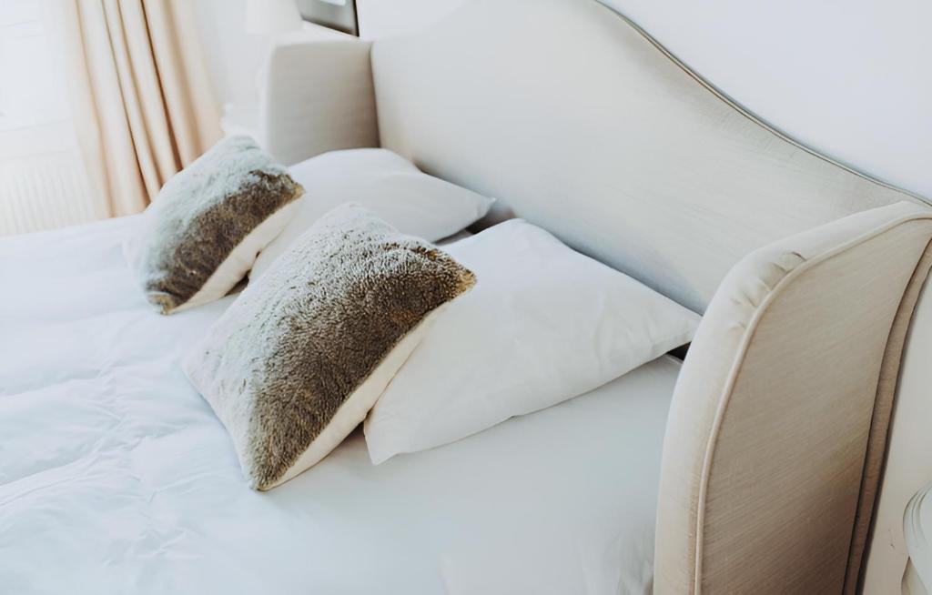 a white bed with three pillows on it at Kasteelhof van Loppem in Loppem