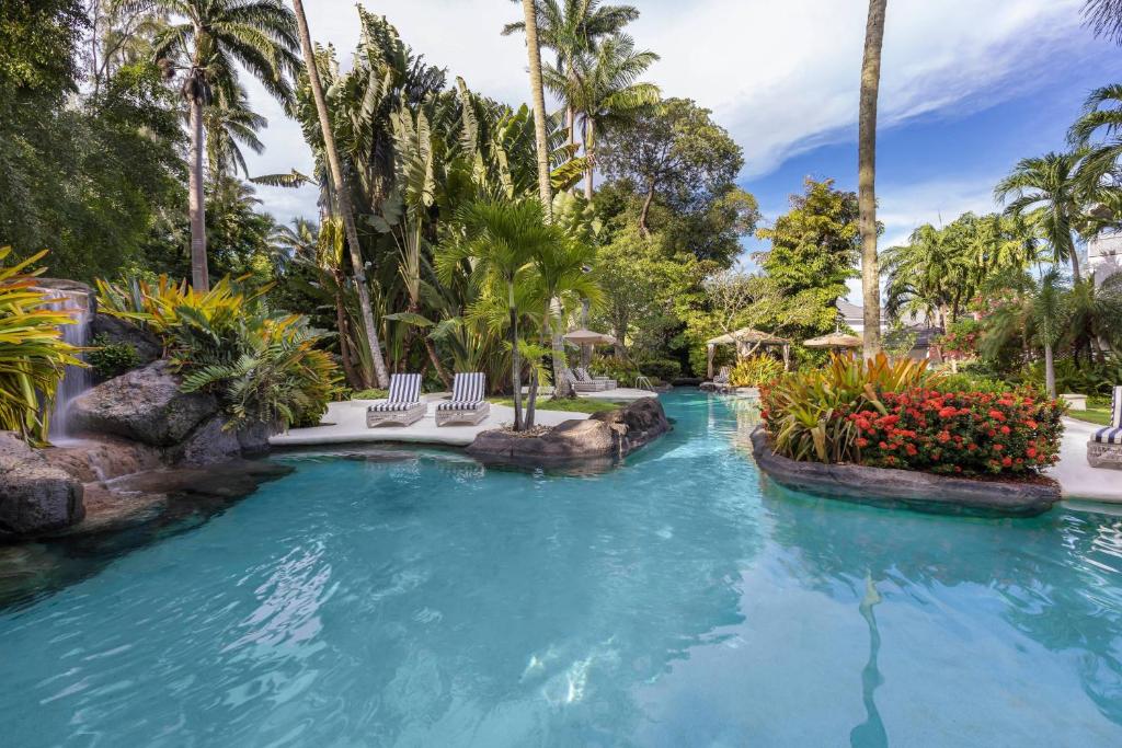 a pool at a resort with chairs and palm trees at Colony Club by Elegant Hotels in Saint James