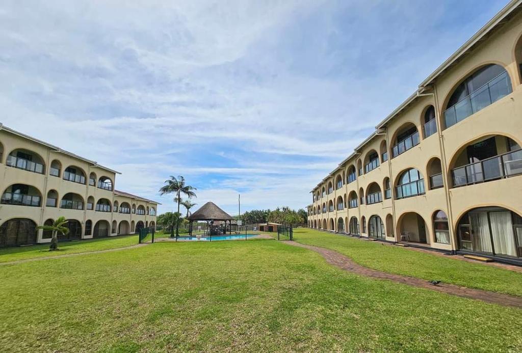 ein großes Gebäude mit einem Spielplatz im Hof in der Unterkunft 16 Cabanas Del Mar Winklespruit KZN South Coast in Kingsborough