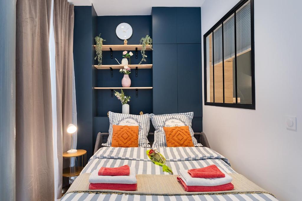 a bedroom with blue walls and a bed with pillows at Guestrust - Champeret Porte Maillot - Ternes in Paris