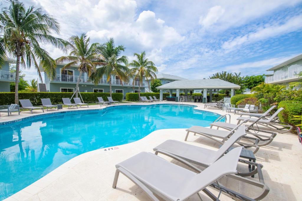 a swimming pool with lounge chairs and palm trees at Summertime Suites #50 in West Bay